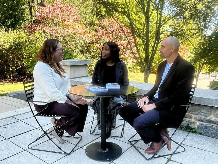 Three people around an outdoor table talking